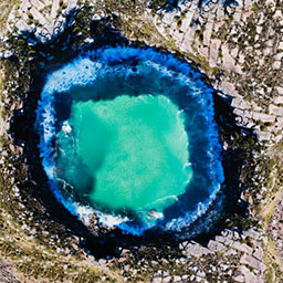 circular aerial landscape, green-blue water in the centre, dark blue edge, greenery surrounding.