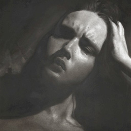 A close up portrait of a young woman's face in low lighting.