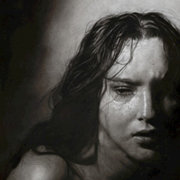 A black and white portrait of a young woman with long hair in low lighting.