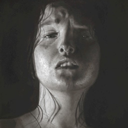 A close up portrait of a young woman's face in low lighting.